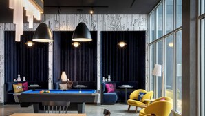 Un área de lounge moderna con mesa de billar, sofás y sillones amarillos.