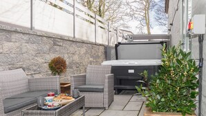 An outdoor patio area with wicker furniture, a hot tub, and a potted plant. - Charming Cornish cottage with private hot tub/shared pool, nr Falmouth/Helford (Falmouth)