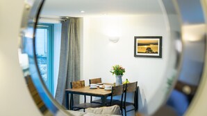 A dining area with a table, chairs, a vase with flowers, and a framed picture on the wall. - Charming Cornish cottage with private hot tub/shared pool, nr Falmouth/Helford (Falmouth)