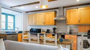 Una cucina moderna con mobili in legno, un forno a microonde, un bollitore e una lavatrice.