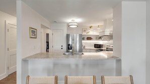 A modern kitchen with a central island, stainless steel appliances, and a bar seating area. - Summer House 109 - 30 Seconds to Sand! (Isle of Palms)