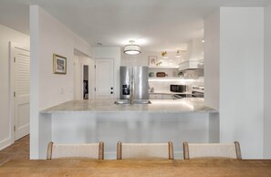 A modern kitchen with a central island, stainless steel appliances, and a bar seating area.