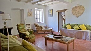 A living room with a sofa, armchairs, a table, and a hanging basket.