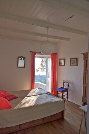 Una camera da letto con un letto, una sedia, un tavolo e una vista dalla finestra.