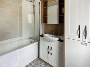 A bathroom with a bathtub, a sink, and a mirror.