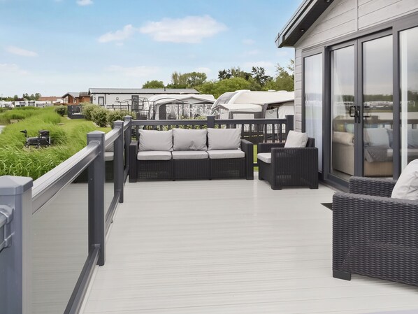 A deck with outdoor furniture, a glass door, and a view of other buildings.