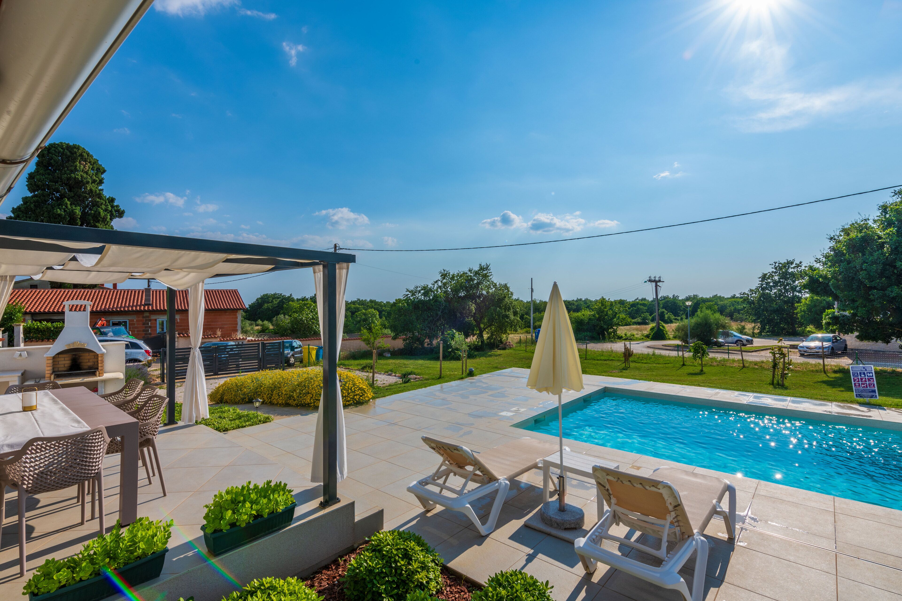 Un espace aménagé au bord de la piscine, avec des chaises longues, une table et un barbecue.