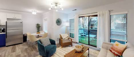 Relax in this inviting living space with a central seating area, dining table, and balcony access.