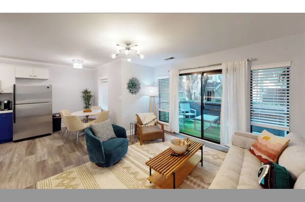 Relax in this inviting living space with a central seating area, dining table, and balcony access.