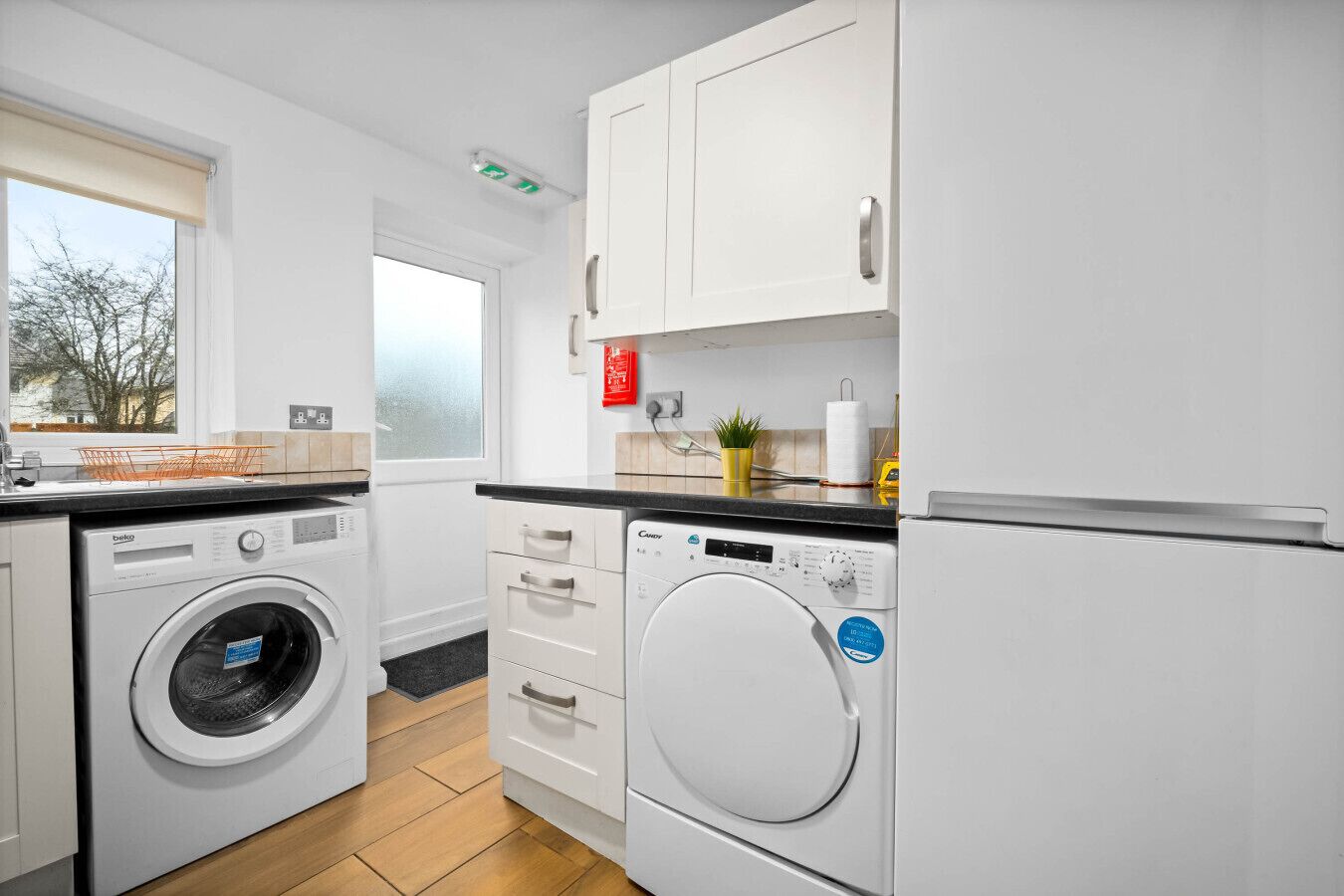 A modern kitchen with a washing machine, a dryer, and a refrigerator.