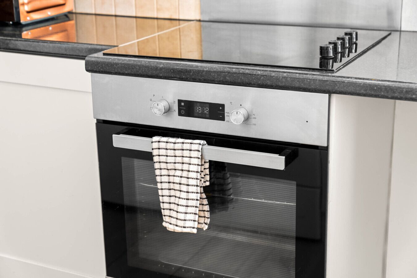 Une cuisine moderne dotée d’un four en acier inoxydable, d’un panneau de commande numérique et d’un plan de travail noir.