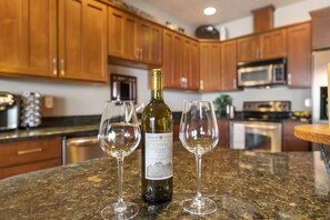 A kitchen counter with a wine bottle and two glasses.