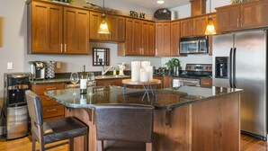 Una cocina moderna con armarios de madera, electrodomésticos de acero inoxidable y una isla central con asientos.