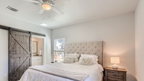 A bedroom with a large bed, a wooden wardrobe, a ceiling fan, and a bedside table with a lamp. - Canyon Lake Retreat, Pets Welcome. WIFI, 3 blocks from boat ramp 6 (Canyon Lake)