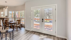 A spacious dining area with a wooden table and chairs, a small round table with a decorative item, and a view through a glass door to an outdoor patio. - Canyon Lake Retreat, Pets Welcome. WIFI, 3 blocks from boat ramp 6 (Canyon Lake)