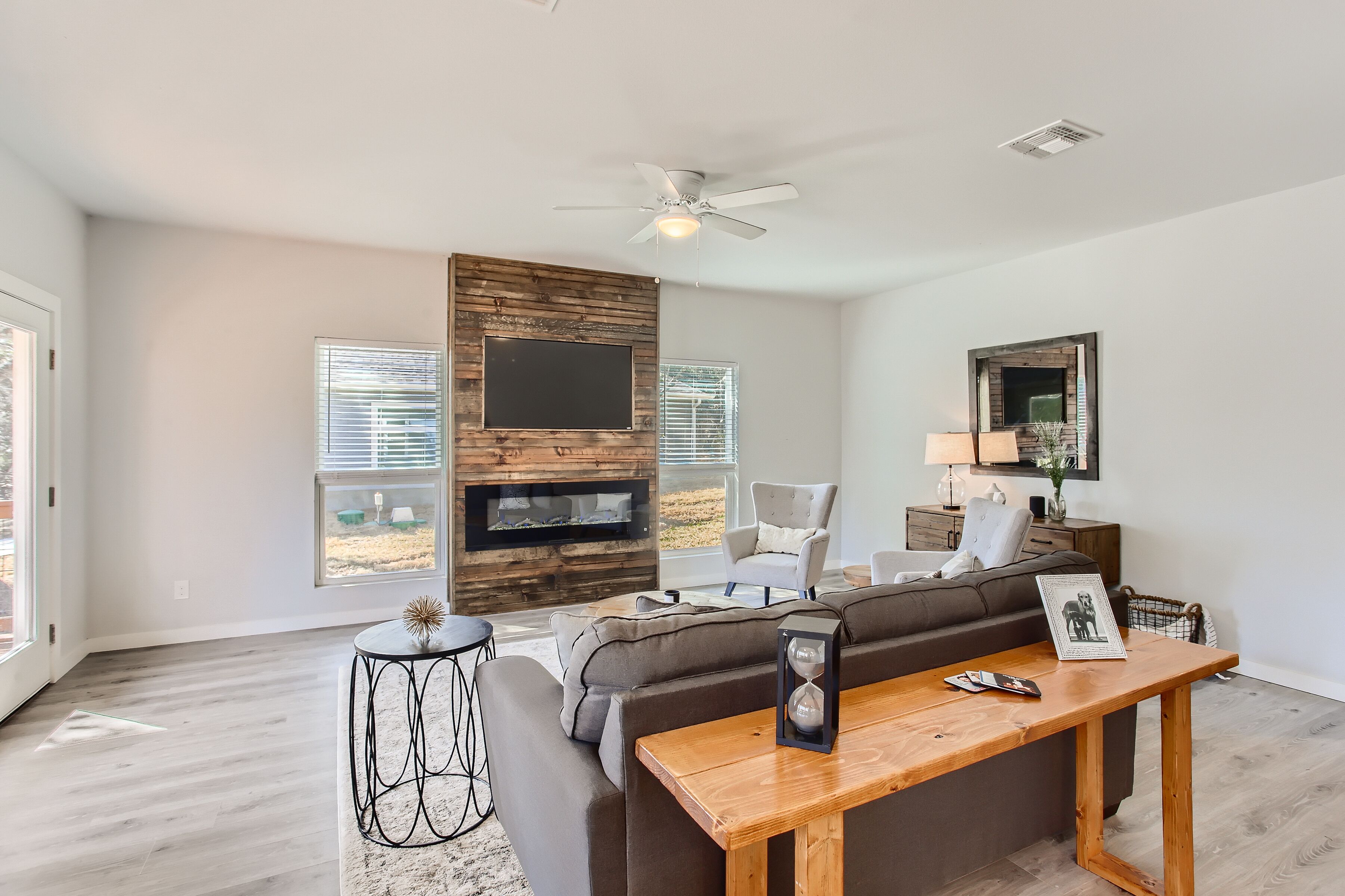 A spacious living room with a fireplace, modern furniture, and large windows.