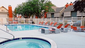 Une piscine avec des chaises longues et un espace délimité par une clôture.