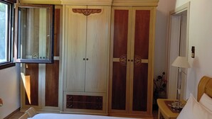 A bedroom with a bed, a wardrobe, a mirror, and a bedside table.