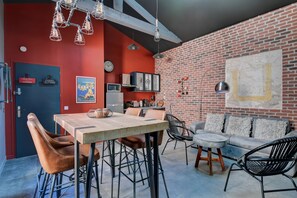 A modern kitchen with red walls, a brick accent wall, and a dining area with a wooden table and leather chairs. - Industrial loft, Forville, downtown Cannes (Cannes)