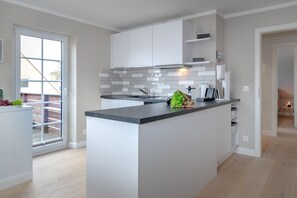 Una cucina moderna con isola centrale, mobili bianchi e un'ampia finestra.