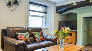 A living room with a leather sofa, wooden coffee table, and a TV.