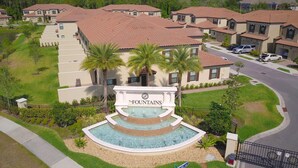 A residential area with a central fountain labeled "The Fountains," surrounded by houses with red-tiled roofs and palm trees.