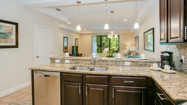 A modern kitchen with granite countertops, stainless steel sink, and dark wooden cabinets.
