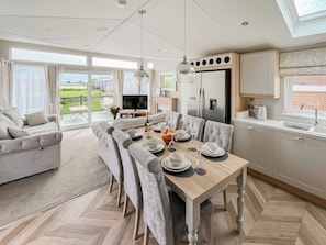 A modern kitchen with a dining area, large windows, and a view of the outdoors.