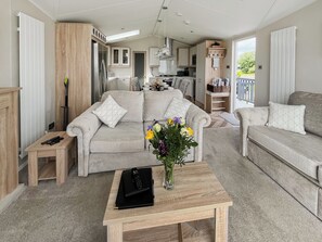 Ein modernes Wohnzimmer mit einer Couch, einem Couchtisch und einer Küche im Hintergrund.