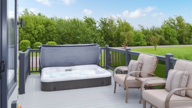 A hot tub on a deck with chairs and a view of a green landscape. - Reel Paradise - UK37723 (Addlethorpe, near Skegness)