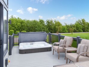 A hot tub on a deck with chairs and a view of a green landscape. - Reel Paradise - UK37723 (Addlethorpe, near Skegness)