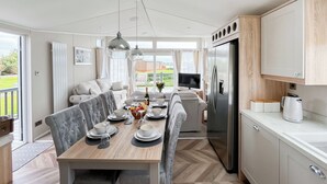 A modern kitchen with a dining area, a refrigerator, and a view of the outdoors. - Reel Paradise - UK37723 (Addlethorpe, near Skegness)