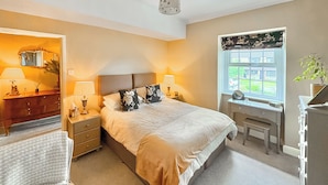 A bedroom with a bed, bedside tables, a desk, a dresser, a window with a view, and a mirror. - 2 bedroom accommodation in Gargrave, near Skipton (Skipton)