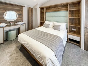 Une chambre à coucher avec un lit, un bureau, un miroir et une armoire.