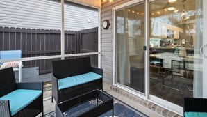 An outdoor patio with wicker furniture, a glass sliding door leading to a kitchen, and a wooden fence. - THIS MUST BE THE PLACE-House to Beach in 5 minutes (Navarre)