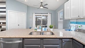 A kitchen with granite countertops, dark cabinets, a ceiling fan, and a window with blinds. - THIS MUST BE THE PLACE-House to Beach in 5 minutes (Navarre)