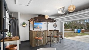 A modern kitchen with a bar area, including a wooden counter, bar stools, and a television. - THIS MUST BE THE PLACE-House to Beach in 5 minutes (Navarre)