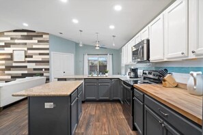 A modern kitchen with dark cabinets, a wooden countertop, and a built-in microwave. - THIS MUST BE THE PLACE-House to Beach in 5 minutes (Navarre)