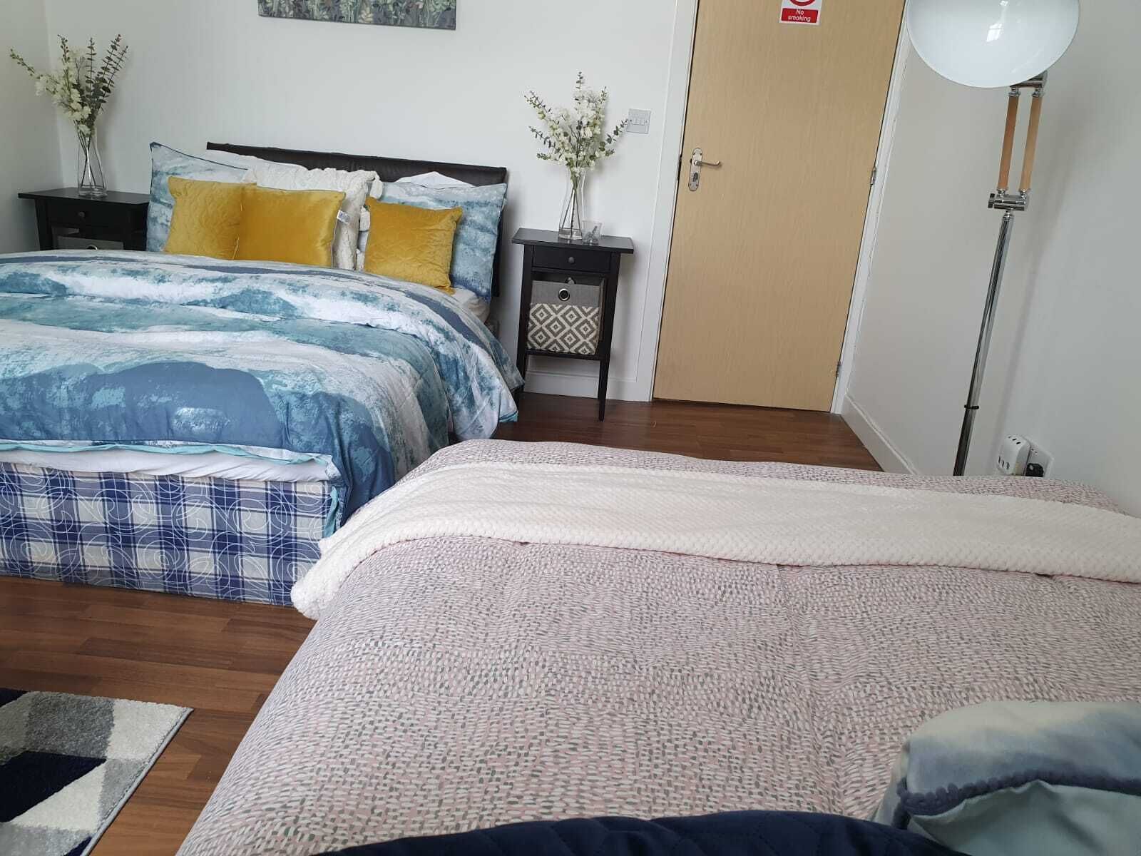 A bedroom with a bed, bedside tables, a lamp, and a door.