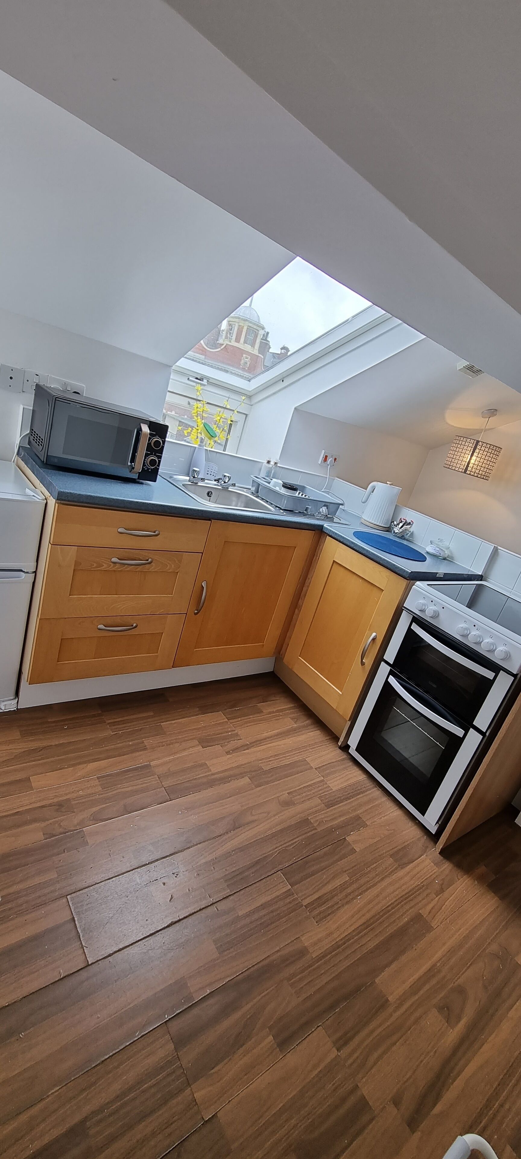A modern kitchen with wooden cabinets, a microwave, and an oven.