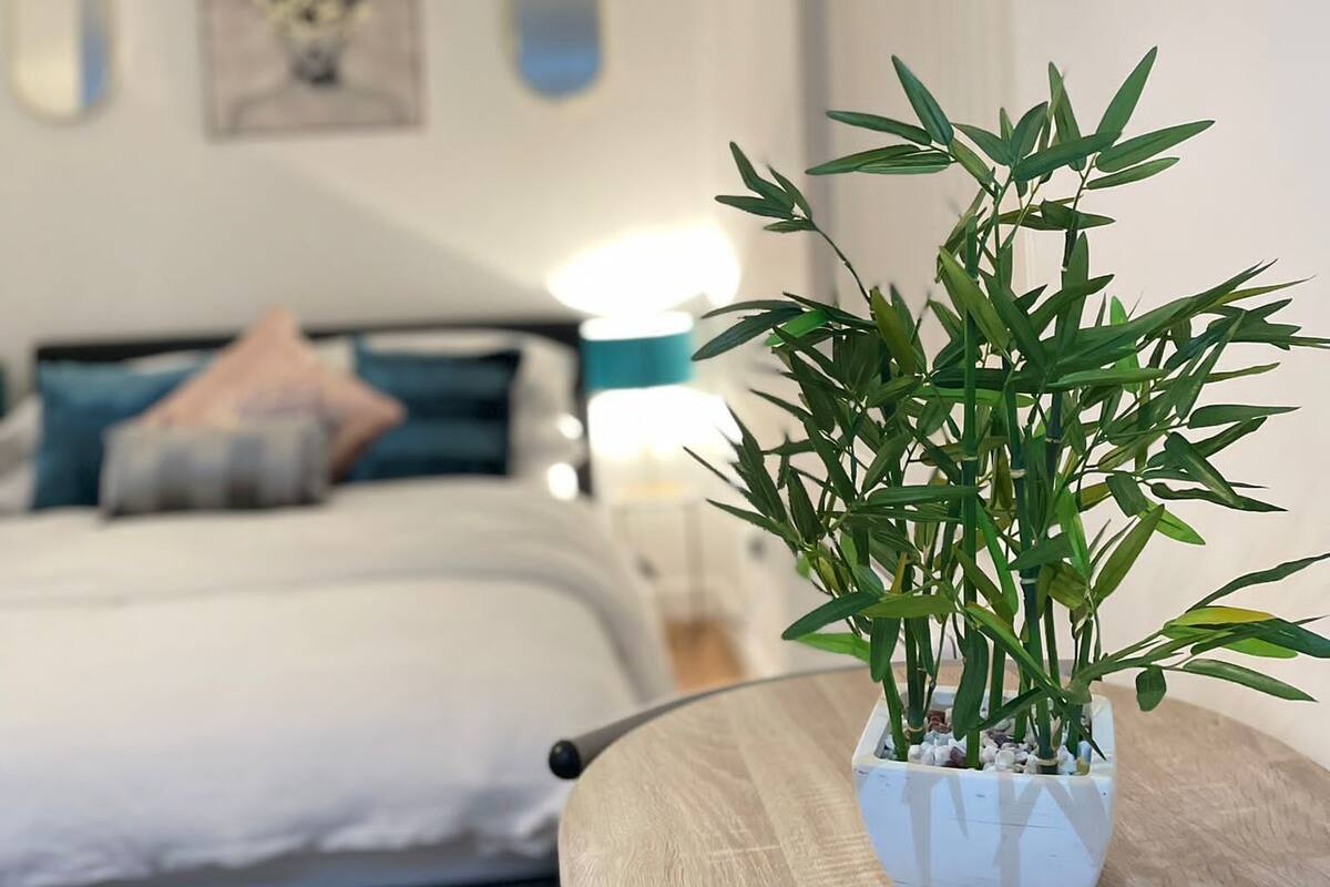A bedroom with a bed, a bedside table, a lamp, and a wall-mounted TV.