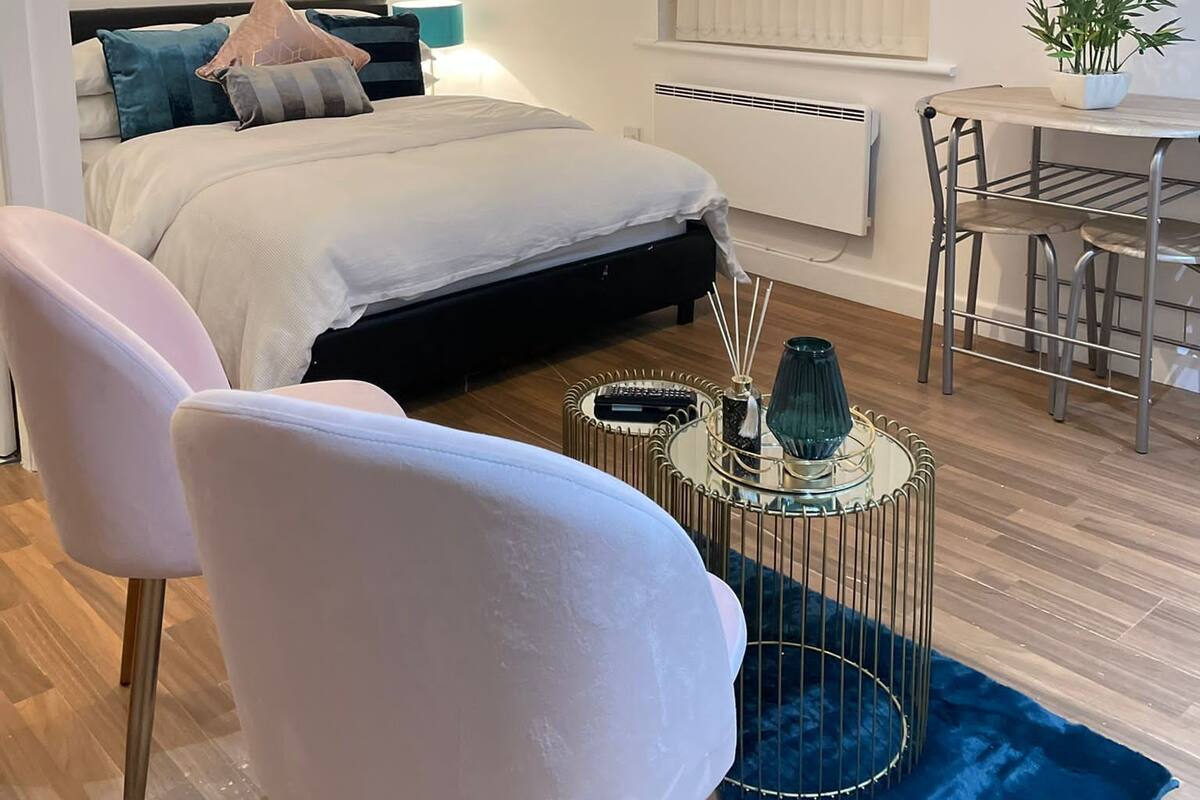 A modern bedroom with a bed, bedside table, chair, and a TV displaying a Netflix advertisement.