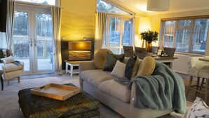A cozy living room with a sofa, ottoman, and a dining table. - Hollicarrs - The Rushes (York)