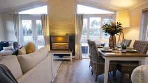 A cozy living room with a sofa, a dining table set for two, and a fireplace. - Hollicarrs - The Rushes (York)