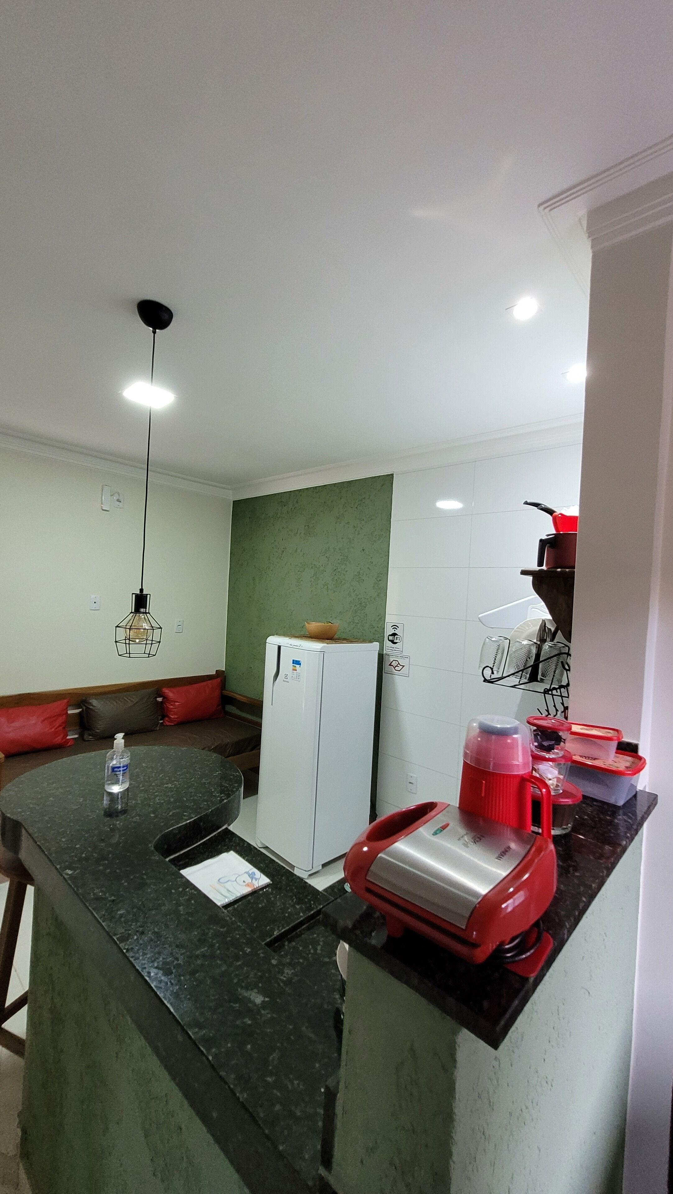 Una cocina compacta con una isla central, un refrigerador y un microondas.