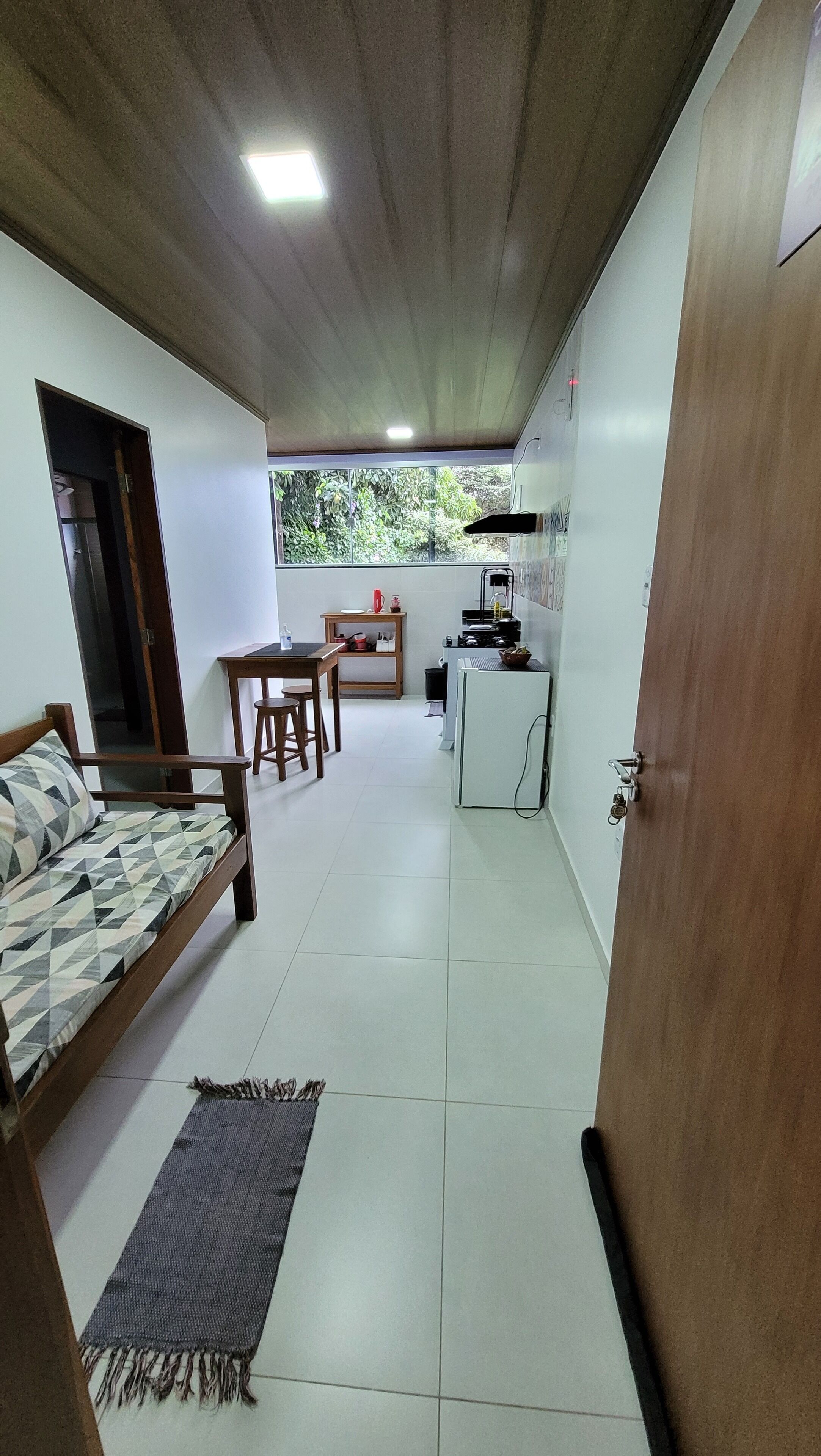 Una habitación compacta con cama, una pequeña mesa de comedor y un rincón cocina.