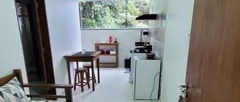 Una habitación compacta con cama, una pequeña mesa de comedor y un rincón cocina.