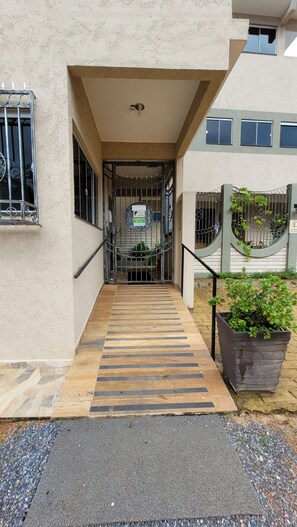 A building entrance with a gated door, a wooden ramp, and a potted plant. - Guest Apartment Village São Jorge (Alto Paraíso de Goiás)