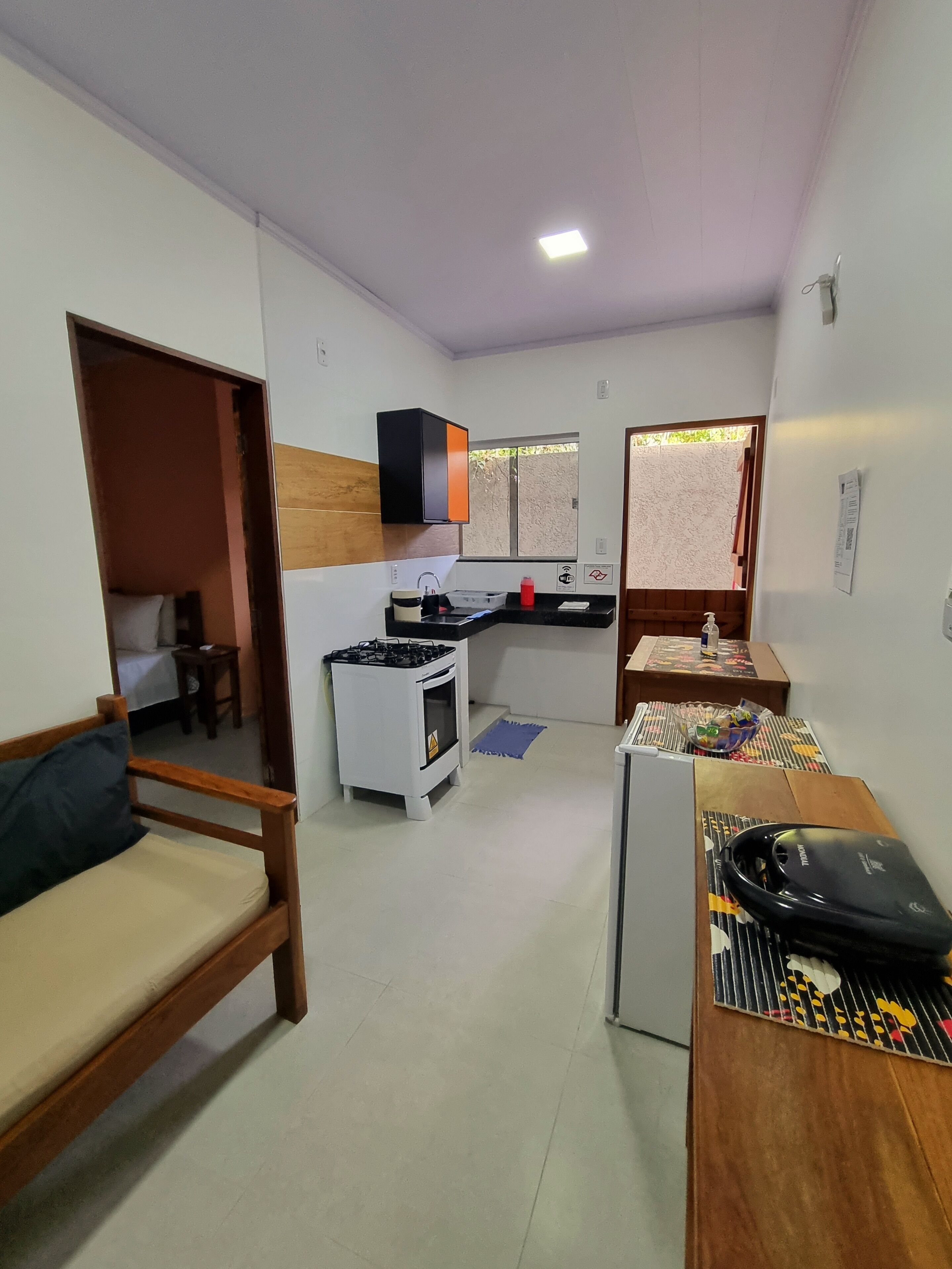 Un espacio habitable compacto con kitchenette, un sofá, una pequeña mesa y un microondas.