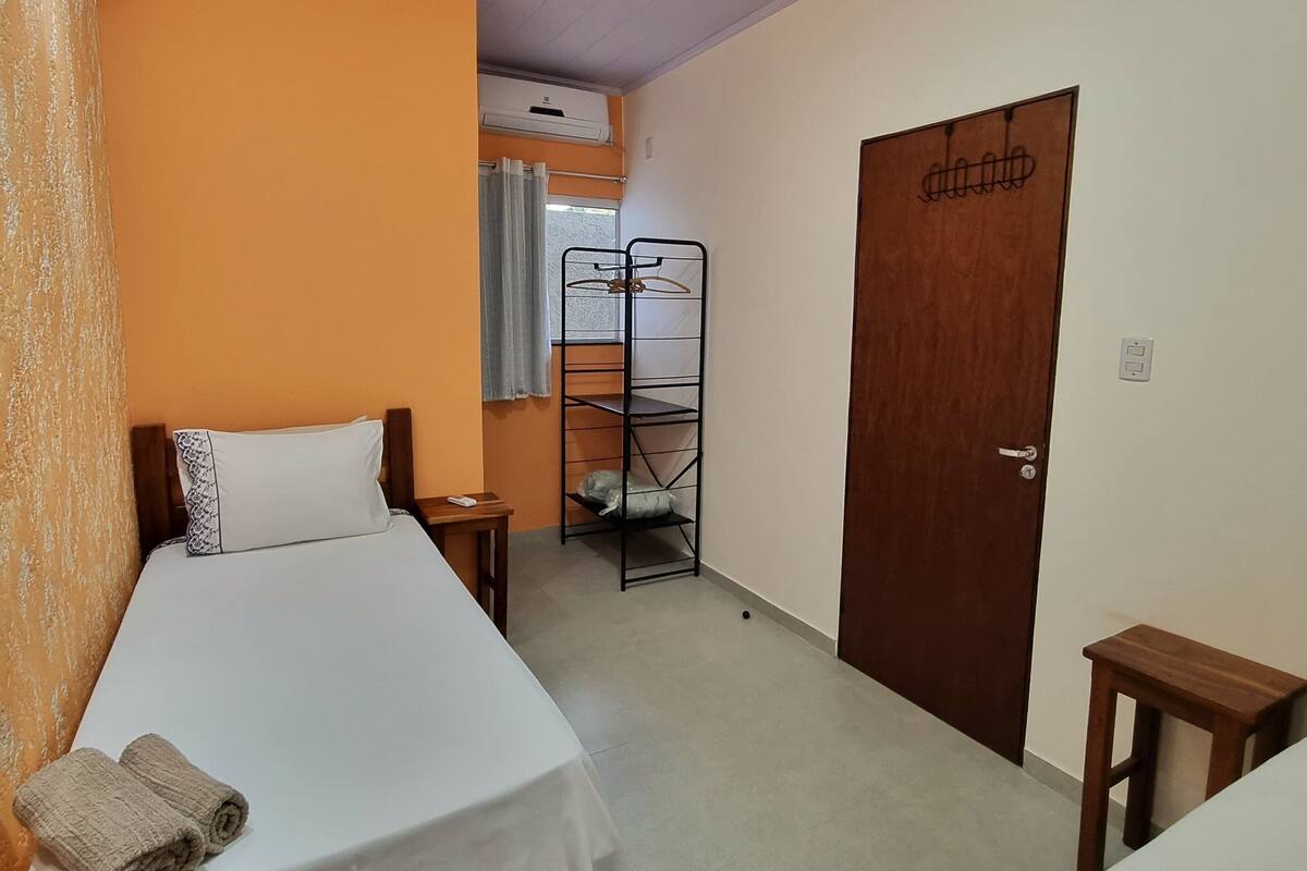 A hotel room with a bed, a wooden door, a wardrobe, and a small table.